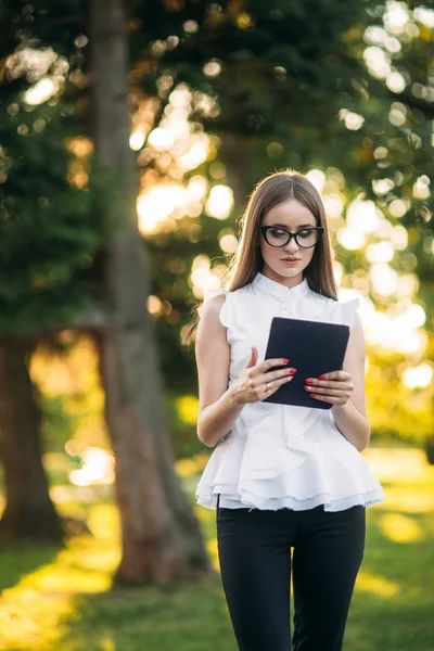 Jonge lerares met tablet buiten. Moderne leraar in het park. Vrouw draagt een bril — Stockfoto