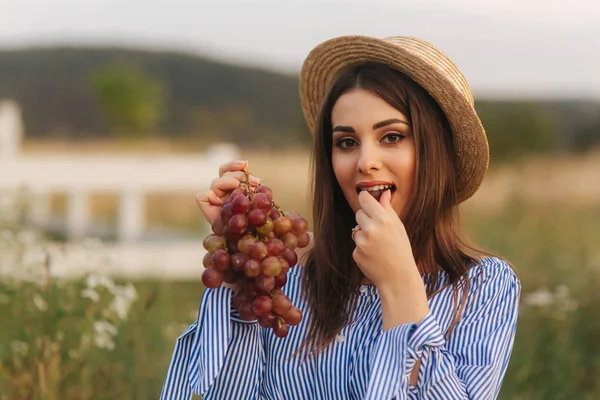 Hermosa mujer embarazada mostrar y comer uvas rojas. Comida saludable. Frutas frescas. Mujer feliz sonrisa — Foto de Stock