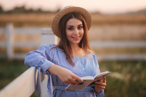 Hermosa mujer embarazada leyó el libro en la granja. Ella está al lado de la novia y mira el libro. Relájate. — Foto de Stock