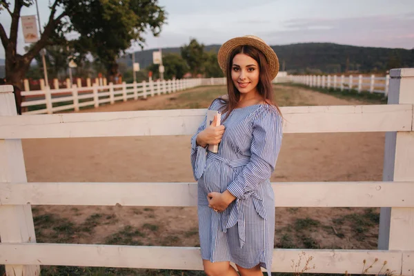 Glad gravid kvinna håller en bok i sin händer och leende. Utsidan — Stockfoto