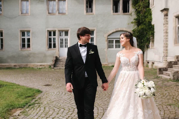 Lycklig bara gifta par i bröllop kläder går nära slottet — Stockfoto