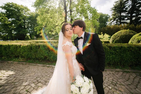 公園でハンサムな新郎と美しい白いウェディングドレスでエレガンド花嫁。緑の背景 — ストック写真