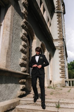 Siyah takım elbiseli yakışıklı damat merdivenlerden iniyor