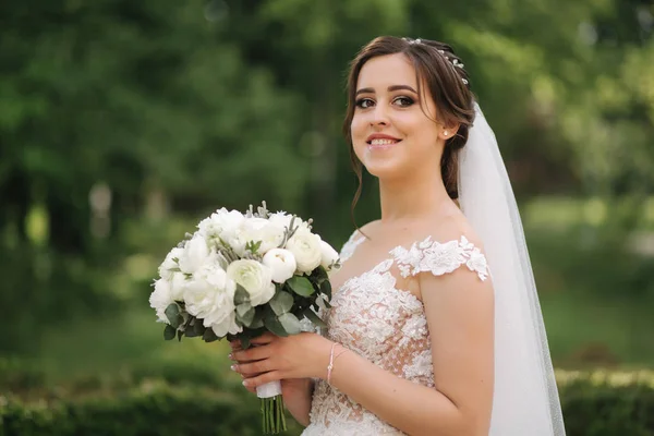 Bela noiva em vestido de noiva andando no parque — Fotografia de Stock