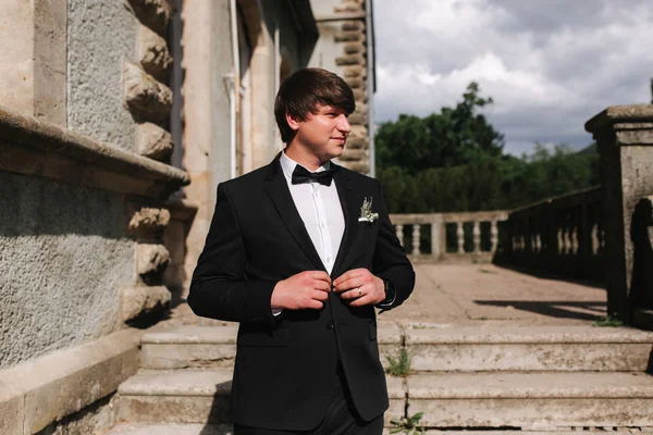 Schöner Bräutigam im schwarzen Anzug geht die Treppe hinunter — Stockfoto