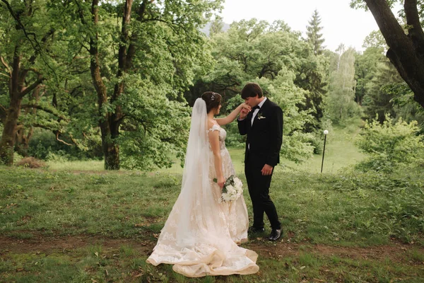 Appena sposati coupleon sfondo verde, scopa e sposa a piedi nella foresta — Foto Stock