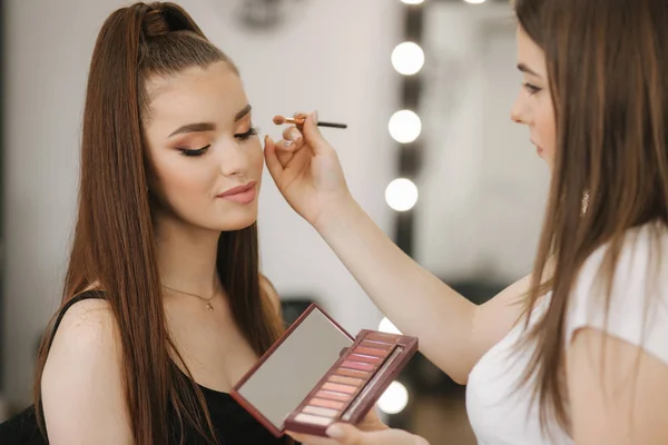 Makeup artist work in her beauty studio. Woman applying by professional make up master. Beautiful make up artist make a makeup for redhead model with freckles. She use a palette — Stock Photo, Image