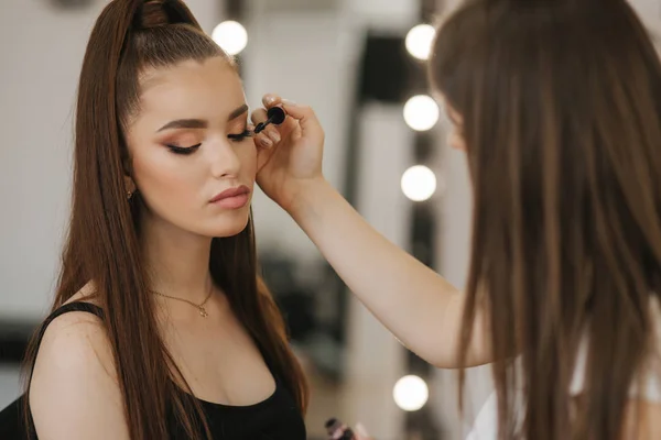 Maquiagem artista trabalho em seu estúdio de beleza. Mulher aplicando pelo mestre de maquiagem profissional. Linda maquiagem artista fazer uma maquiagem para ruiva modelo com sardas. Ela usa uma paleta. — Fotografia de Stock