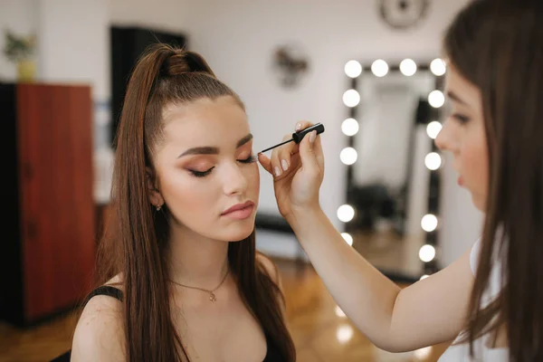 Maquiagem artista fazendo profissional compõem de jovem ruiva mulher com sardas — Fotografia de Stock