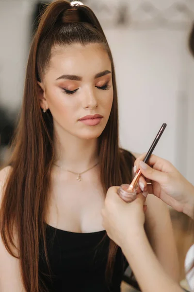 Makeup artist applies eye shadow, perfect evening makeup. Beauty redhead girl with perfect skin and freckles. Closeup — Stock Photo, Image