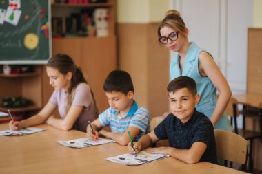 Öğretmenler sınıfta öğrencilerin yazma sınavına yardım ediyor. eğitim, ilkokul, öğrenim ve insanlar konsepti