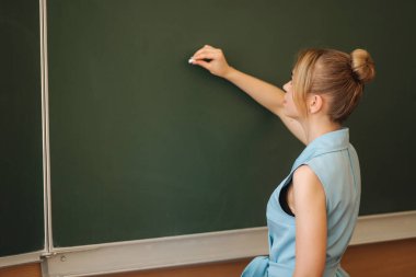 Bayan öğretmen okul masasında mezgit kazıyor. Genç öğretmen.