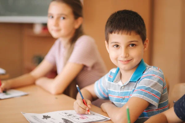 Boy and girl sitting at desk and writing a text — Stock Photo, Image