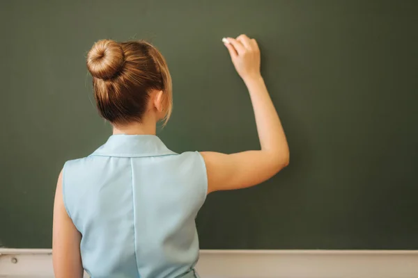 Женщина-учитель отбеливает что-то на школьном столе. Молодой учитель — стоковое фото
