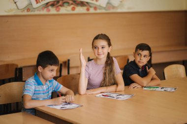Eğitim, ilkokul. Öğrenme ve insan konsepti - kalemi ve not defterleri olan bir grup okul çocuğu sınıfta yazı sınavı