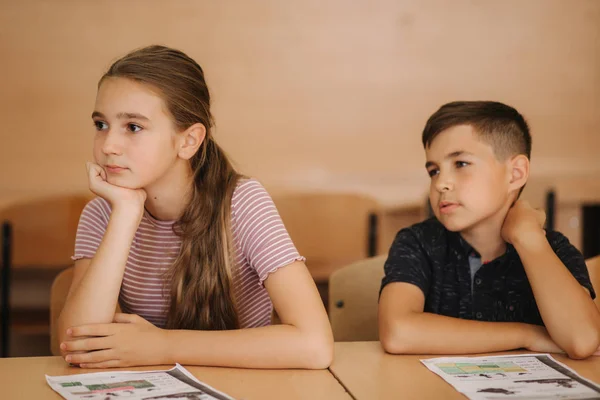 教室でペンとノートを書くテストを持つ学校の子供たちのグループ。教育、小学校、学習、人の概念 — ストック写真