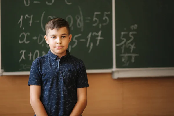 Sevimli çocuk tahtanın sınıf arka planda durmak. Eğitim. Ilkokul — Stok fotoğraf