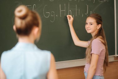 Liseli kız sınıfta tahtaya bir şeyler yazıyor