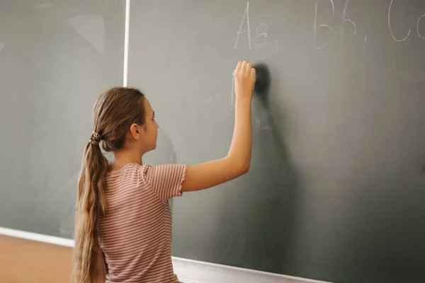 教室の黒板に何かを書く女子高生 — ストック写真