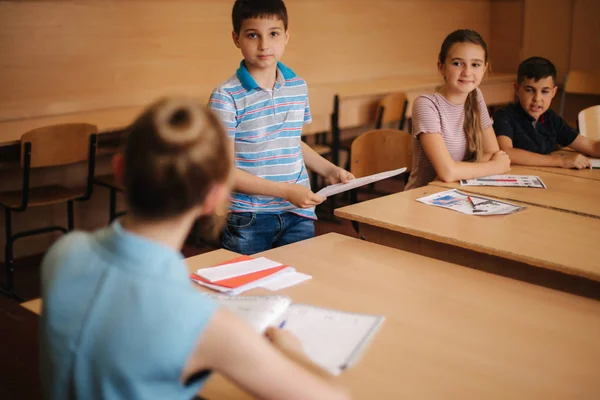 Bonita maestra en el aula sentada en el escritorio y preguntando a los niños. educación, escuela primaria, aprendizaje y concepto de personas — Foto de Stock