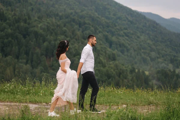Vőlegény és a menyasszony gyalogos hougt a Kárpátok hegyei — Stock Fotó