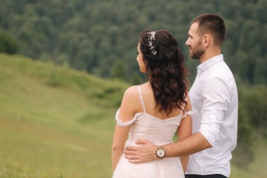 Güzel genç düğün çift yeşil yamaç, tepe üzerinde ayakta. Karpat dağlarında damat ve gelin