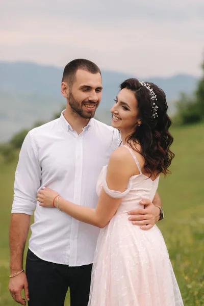 Hermosa joven pareja de boda de pie en la pendiente verde, colina. Novio y novia en las montañas Cárpatos — Foto de Stock