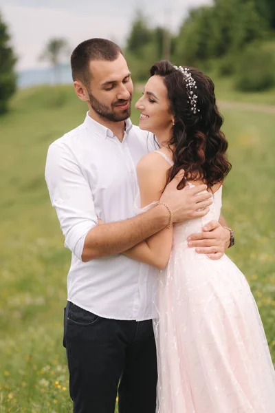 Casal jovem bonito de pé na encosta verde, colina. Noiva e noivo nas montanhas dos Cárpatos — Fotografia de Stock