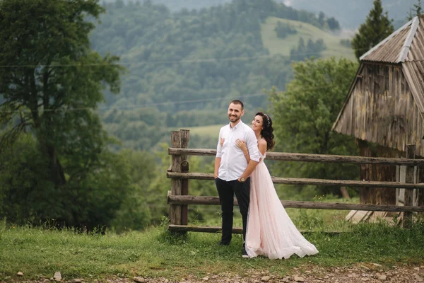 매력적인 신부는 산에서 그녀의 잘 생긴 신랑을 포옹. 아름다운 결혼식 부부 산책. 그린 게이크그라운드 — 스톡 사진