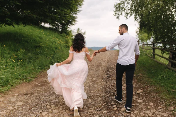 Przystojny mężczyzna prowadzi swoją narzeczoną do pięknych Karpat. Szczęśliwa para ślubna — Zdjęcie stockowe