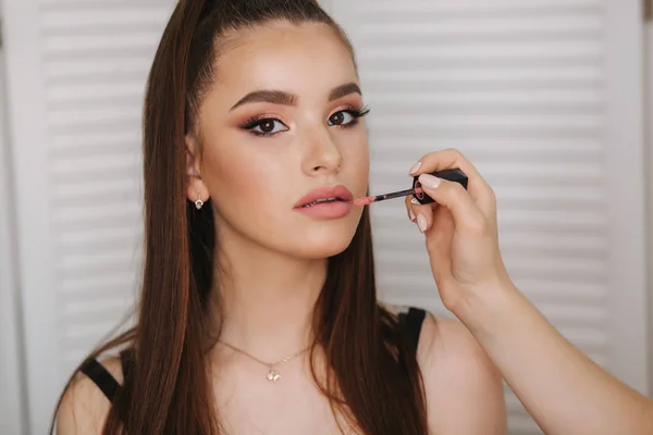 Mano di trucco artista tenere pennello rossetto e fare il trucco. Bel sorriso da modella. Sfondo dello schermo pieghevole bianco — Foto Stock