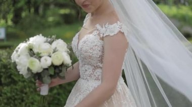 Muhteşem gelinlik Büyüleyici gelin tutun buket ve çiçek açan ağaçların önünde durmak