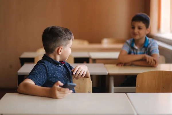 Sevimli küçük çocuk ders sırasında telefon kullanın. Sınıfta iki schollboy — Stok fotoğraf