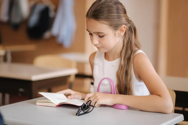 Schoolmeisje neem een notitieboekje en schrijf huiswerk op — Stockfoto