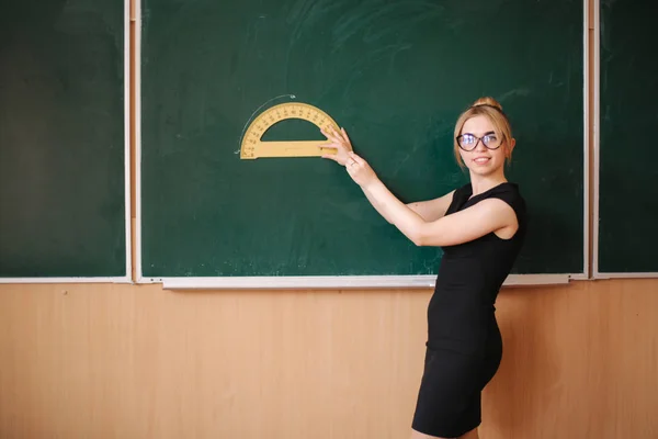 眼鏡の若い女性教師が黒板の前に立つ — ストック写真