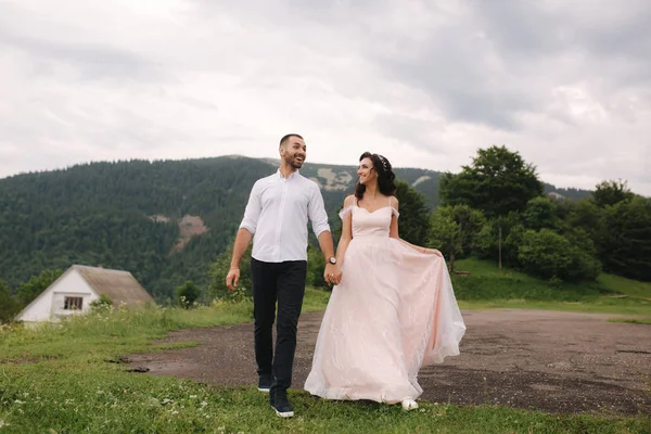 Mooie jonge bruidspaar staan op de groene helling, heuvel. Bruidegom en bruid in de Karpaten — Stockfoto