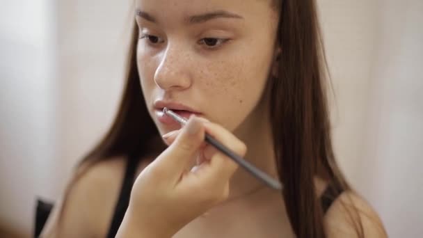 Makeup artist applicerar läppstift. Hand make-up Master, målning läppar av ung skönhet rödhårig modell. Göra upp i processen. Närbild Visa — Stockvideo