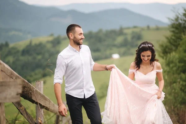 Casal jovem bonito de pé na encosta verde, colina. Noiva e noivo nas montanhas dos Cárpatos — Fotografia de Stock