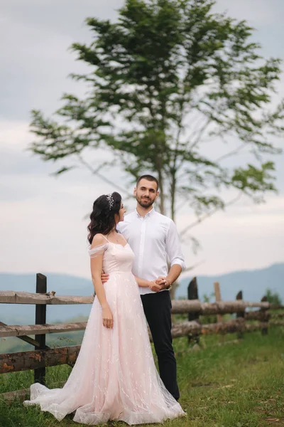 Lovestory de beau couple dans les montagnes, bel homme barbu avec belle et charmante femme. Couple debout devant un bel arbre — Photo