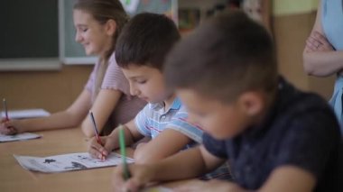 Öğretmenler sınıfta öğrencilerin yazma sınavına yardım ediyor. eğitim, ilkokul, öğrenim ve insanlar konsepti