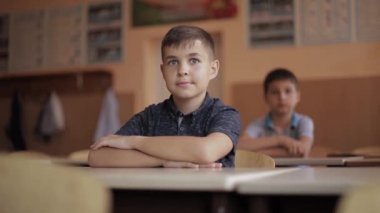 İlkokuldaki mutlu küçük çocuklar. Erkekler ve kızlar okuyor. Çocuklar el kaldırır