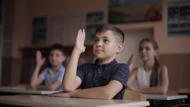 Счастливые маленькие дети в начальной школе. Мальчики и девочки учатся. Дети, поднимите руки — стоковое видео