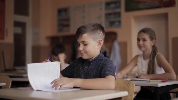 Jongen en meisje zittend op Bureau en het schrijven van een tekst — Stockvideo