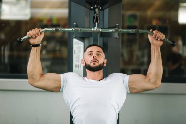 Genç bir atlet spor salonunda eğitiyor. Sırt ve göğüs kaslarının gösterir