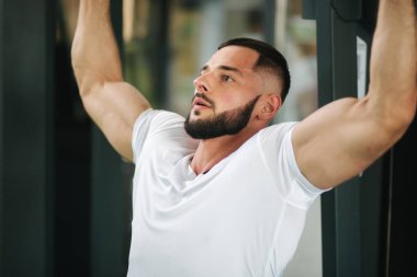 Genç bir atlet spor salonunda eğitiyor. Sırt ve göğüs kaslarının gösterir