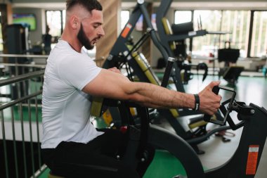 Genç bir atlet spor salonunda antrenman yapıyor. Vücut geliştirici sırt kaslarını eğitir.