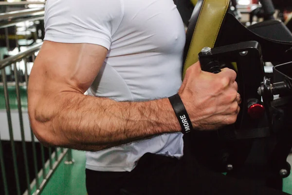 Un joven atleta entrena en el gimnasio. El culturista entrena los músculos de la espalda. Primer plano de mano fuerte —  Fotos de Stock