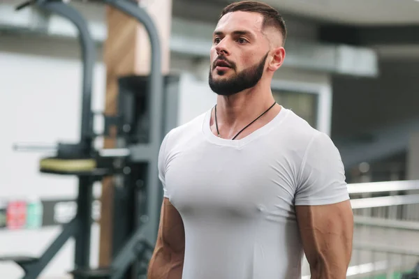 L'uomo usa l'allenamento con elastici in palestra. Uomo in t-shirt bianca treni all'interno — Foto Stock