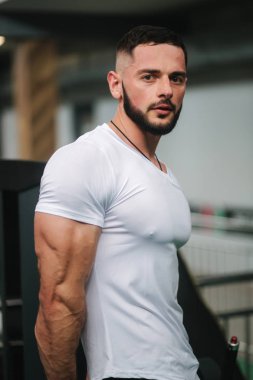 Genç atlet spor salonunda fotoğraf için bir gövde ile poz. Vücut geliştirmeci, pompalı kasları ile atlet, meme ve kol kurtarma. Adam göstermek triceps
