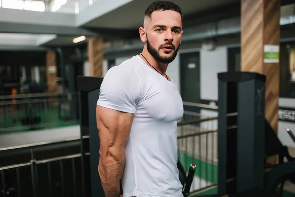 Jovem atleta posando com um tronco para fotografia no ginásio. Fisiculturista, atleta com músculos bombeados, resgate de seios e braços. Homem mostrar tríceps — Fotografia de Stock